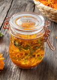 Glass jar with Orange Calendula (Calendula officinalis) tea on a wooden surface