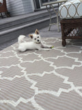 White dog lying on a Casa Blanca Sand & White outdoor rug on a deck.