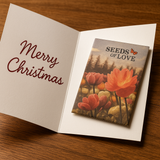 Open card with 'Merry Christmas' text and a seed packet labeled 'Seeds of Love' on a wooden surface.