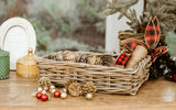 Decorative basket with pinecones, ornaments, and plaid ribbon on a wooden surface with a blurred natural background.