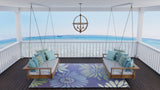 Two wooden swing chairs with blue cushions on a deck with Daisy Blue rug and a scenic ocean view.