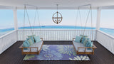 Porch with swing chairs and a Daisy Blue rug overlooking a beach.