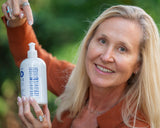 Woman holding a bottle of 'Good World' cleaning product outdoors