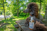 Dog sitting on a wooden bench outdoors with a bottle of ESB CRAFT BEER SOAP ~ 16 oz. LIQUID SOAP