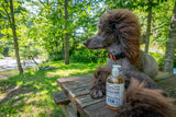 Dog sitting on a wooden table outdoors with a bottle ofESB CRAFT BEER SOAP ~ 16 oz. LIQUID SOAP