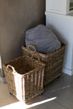 Wicker baskets with a gray fabric item inside, placed against a neutral wall.