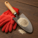 Red gardening glove and trowel with soil on a wooden surface