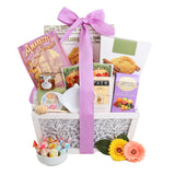 Gift basket with a purple ribbon, cookies, tea, and flowers on a white background Garden of Indulgence Gourmet Gift Basket with Tea & Cookies