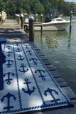 Nautical-themed rug with anchor pattern on a dock by a body of water.