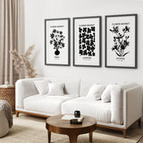 Living room with a white sofa, wooden coffee table, and framed Flower Market Black and White Art Set Decor