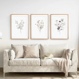Beige sofa with decorative pillows and a blanket, featuring 3 Piece Watercolor Floral Wall Art Set on the wall.