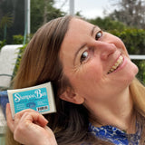 Woman holding a Shampoo Bar container outdoors with greenery in the background
