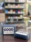 Two bars of soap labeled 'A Slice of the Good Life' on a reflective surface with a blurred store background.