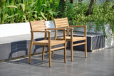 Two wooden chairs on a patio with greenery in the background Julien FSC Certified Teak Wood Outdoor Patio Extendable Dining Set