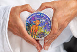 Two hands holding a container of Appalachian Goat Ginger Quince Body Butter with a colorful label.