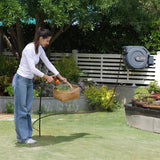 Woman using a hose with a reel in a garden setting