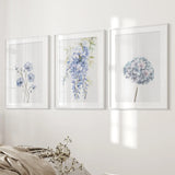 Set of three floral prints on a wall with a neutral color scheme.
