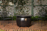Outdoor setting with a fire pit table and chairs against a lattice wall.