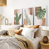 Bedroom with decorative wall art featuring 3 Piece Terracotta Boho Wall Art. Green Tropical Leaves and a lamp.