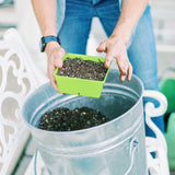 Person holding a green container of seeds over a bucket of soil. 5x5 Deep Grow Tray Inserts