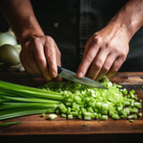 Person chopping celery on a wooden cutting board with a knife.