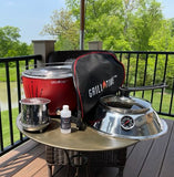 Outdoor setting with a grill and accessories on a table, surrounded by greenery.