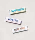 Three packages of seed balls labeled 'Grow Comfort', 'Grow Love', and 'Grow Peace' on a light background.