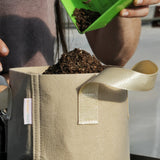 Person adding soil to a f2 Gal Grow Bag - Tan with a green tool.