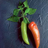 Two green and one red chili pepper on a dark textured surface HOT PEPPER Seeds, Anaheim Chili