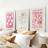 Keith Haring & Matisse Pink Set of 3 Prints on a wall above a bed with pillows and a lamp.