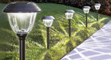 Set of solar-powered garden lights on a grassy area with a pathway.