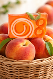 Orange soap bar with green leaves on top of peaches in a woven basket