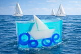 Soap bar with sailboat design on a blue background, with sailboats in the distance.