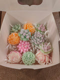 Colorful flower-shaped candles in a box on a brown surface
