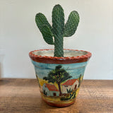 Cowboy Prickly Pear in a decorative pot with a painted landscape on a wooden surface