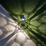 Garden light fixture casting shadows on grass and pavement