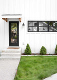 Modern house exterior with a black door and white walls, featuring a well-maintained lawn and small trees. EcoSeed - The No Maintenance Lawn, Fine Fescue Lawn Mix, Eco-Friendly Grass