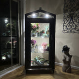 Janco Indoor/Outdoor Garden Cabinet with plants on a wooden floor next to a sliding glass door.