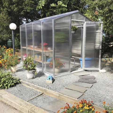 Janco Palmetto Greenhouse greenhouse in a garden with flowers and plants around