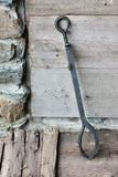 Black metal fire tongs against a rustic wooden and stone background