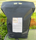 Black bag with Worm Castings label on a green surface with plants in the background 