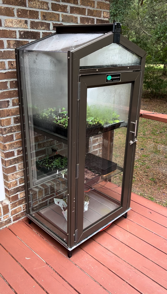 Janco Indoor/Outdoor Garden Cabinet attached to a brick wall with plants inside