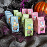Assorted children's product packages on a textured surface with pumpkins in the background Magical Plops