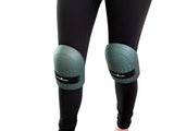 Green knee pads worn by a person on a white background