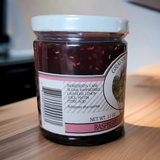 Jar of raspberry jam with a visible label on a wooden surface