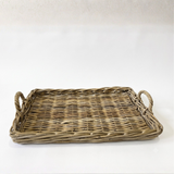 A rectangular woven wicker tray with two loop handles, shown on a plain white background.