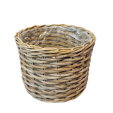 A natural woven wicker basket with a clear plastic liner inside, shown on a plain white background.