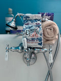 Box of 'Salt for the Tub' Essential Soaps on a bathtub faucet with a blue wall background.