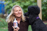 Woman holding a bottle of LAVENDER GOATS MILK LOTION next to a black dog outdoors