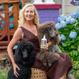 Woman holding two poodles and a bottle of LIQUID SOAP ~ LEMONGRASS GOATS MILK LIQUID SOAP 16 oz. NEW LABEL in a garden setting